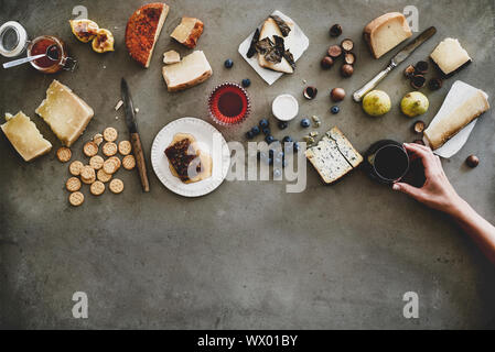 Käse, Honig, Obst, Nüsse, Kekse und Weinglas in weiblicher Hand Stockfoto