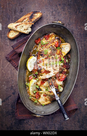 Gebratene John Dory Fischfilet mit Gemüse und Baguette als Top-Ansicht in eine Kasserolle Stockfoto
