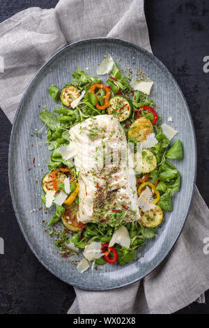 Frittierter Kabeljau Filet mit Salat und Gemüse als Draufsicht auf einer Platte Stockfoto