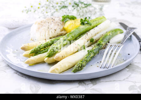 Dorsch Filet mit grünem und weißem Spargel und Kartoffeln als Top-Ansicht auf einer Platte Stockfoto