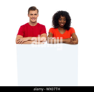 Junges Paar hinter weißen Billboard Blick in die Kamera Lächeln Stockfoto