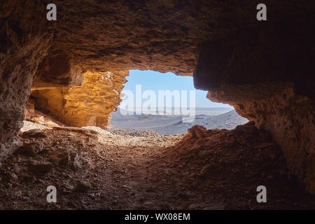 Blick aus dem Inneren der Höhle auf die steinige Wüste in der Sahara im Sudan liegen unter einem glitzernden Sonne. Stockfoto