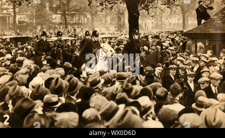 Der berittenen Polizei und Demonstranten, bedeutet Test Proteste, Hyde Park, London, 1932, (1933). 'D"Demonstratoren unter Eskorte". Die nationalen Hunger März von September bis Oktober 1932 war der größte einer Reihe von Hunger marschiert in Großbritannien. Die Arbeitslosenquote erreicht 2.750.000 Arbeitslose, die 1932 nationalen Arbeiterbewegung organisiert Große nationale Hunger März gegen die Bedürftigkeitsprüfung, Marsch von der South Wales Täler, Schottland und Nordengland zum Hyde Park in London. Von "Der Festzug des Jahrhunderts". [Odhams Press Ltd, 1933] Stockfoto