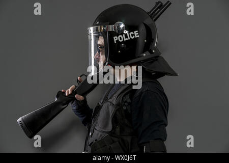 Guard Polizist mit voller Ausrüstung für Anti-Riot, Law Enforcer in Schützende Uniform bereit für Crowd control isoliert auf Schwarz Stockfoto