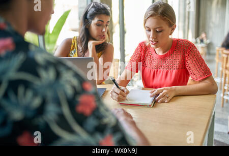 Candid lifestyle Schuß von Gruppe von vielfältigen tausendjährigen Mitarbeiter gemeinsam Brainstorming auf Laptop Computer in hellen, modernen Restaurant Stockfoto
