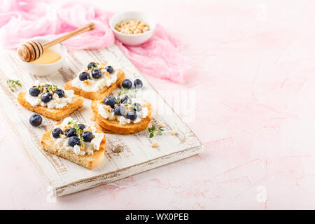 Toast mit frischen Beeren Heidelbeeren Ricotta, Thymian, Honig und Haselnüssen, serviert. Stockfoto