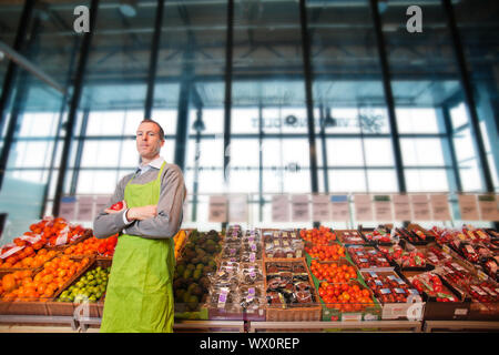 Porträt eines Lebensmittelgeschäft Clkerk oder Eigentümer vor einem Gemüsetheke Stockfoto