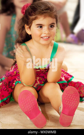 Die Kleine fröhliche baby girl klatschen ein Hände, schöne weibliche Kind sitzen auf dem Boden und beobachten die Leistung für Ihren 3-jährigen Geburtstag, adorable k Stockfoto