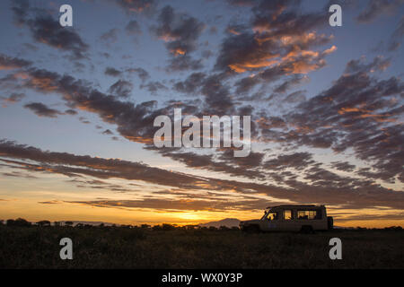 Eine Safari Fahrzeug bei Sonnenaufgang in Ndutu, Serengeti, UNESCO-Weltkulturerbe, Tansania, Ostafrika, Südafrika Stockfoto