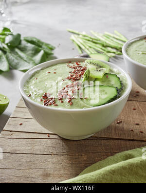 Vegetarische gesunde Smoothies mit Kiwi, Gurke und Leinsamen in einer Platte auf einem Holzbrett Stockfoto