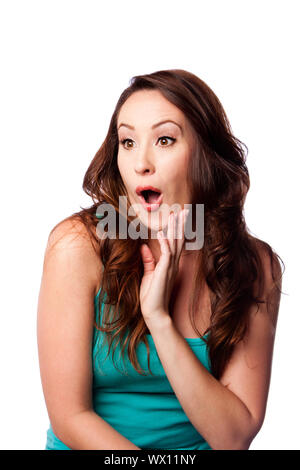 Gesichtsausdruck von einem überrascht, schockiert begeistert junge Frau mit Hand am Kinn und lange gewellte braune Haare, isoliert. Stockfoto