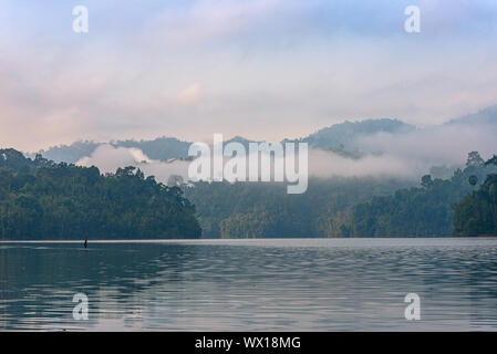 Nebligen Berge am frühen Morgen auf dem Cheow Lan Lake im Nationalpark Khao Sok in Thailand Stockfoto