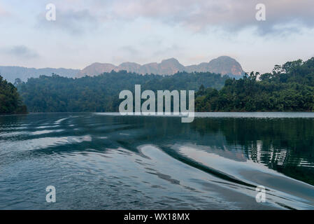 Nebligen Berge am frühen Morgen auf dem Cheow Lan Lake im Nationalpark Khao Sok in Thailand Stockfoto