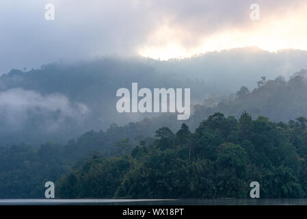 Nebligen Berge am frühen Morgen auf dem Cheow Lan Lake im Nationalpark Khao Sok in Thailand Stockfoto