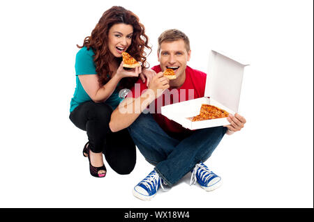 Junges Paar am Boden sitzen und genießen Sie leckeren pizza Stockfoto