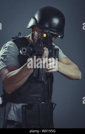 Sicherheit, Paintball-Sport-Spieler tragen Schutzhelm mit dem Ziel Pistole, schwarze Rüstung und Maschinengewehr Stockfoto
