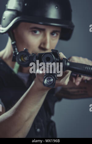 Schüsse, Paintball-Sport-Spieler tragen Schutzhelm mit dem Ziel Pistole, schwarze Rüstung und Maschinengewehr Stockfoto