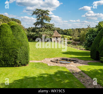 Garten von Great Chalfield Manor in Wiltshire UK mit angehobenem Teich abgeschnitten Eibe Schloss und Gartenhaus Stockfoto