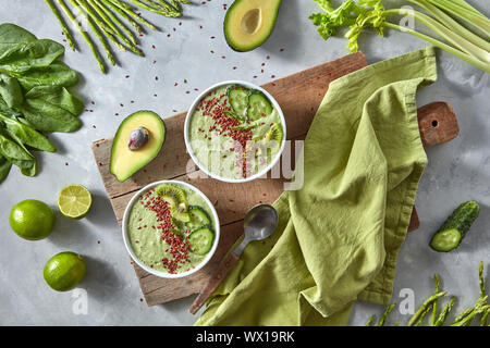 Grüne smoothies von Avocado mit Gurke, Kiwi und Flachs in eine Platte auf einem Holzbrett auf grauem Beton Hintergrund. Gesunde fo Stockfoto