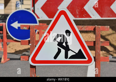 In Arbeit. Baustellen, Verkehrszeichen. Männer an die Arbeit. Barrieren und Verkehrszeichen. Pfeil nach links. Stockfoto