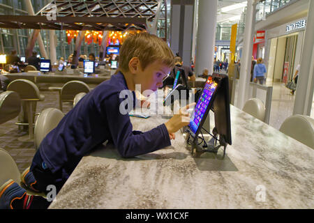 Sie Kinder spielen mit den öffentlichen Gebrauch ipads im Abflugbereich von Toronto Pearson Flughafen Stockfoto