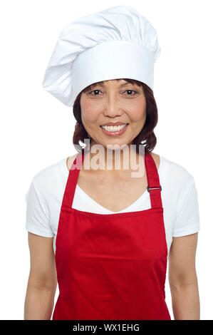 Lächelnde Frau Jungkoch tragen rote Schürze und Haube Stockfoto