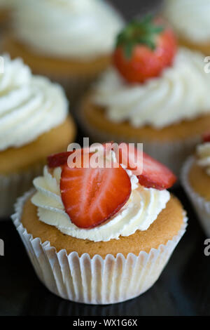 Kleine Kuchen mit Schlagsahne und frischen Erdbeeren dekoriert Stockfoto