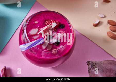 Smoothies von roten Beeren in einem Glas mit Rote Bete, Himbeeren und schwarzen Johannisbeeren, Mandeln auf einem Papier Hintergrund. Stockfoto