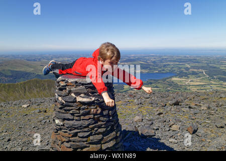 Ein Junge (7 Jahre alt) vorgibt, Superman auf dem Gipfel des Skiddaw im Lake District zu werden. Stockfoto