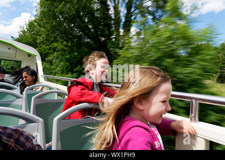 Zwei Kinder lachen mit Wind in ihren Gesichtern auf einem oben offenen Doppeldeckerbus im See Distrcit, Cumbria, Großbritannien Stockfoto