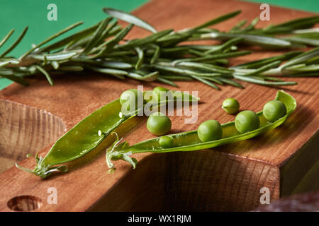 - Nahaufnahme grün Bio Clean Gemüse - Rosmarin, Hülsen der Erbsen Bohnen auf ein Holzbrett auf der Grünen. Stockfoto