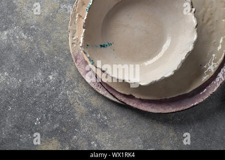 Porzellan leere Schalen und Teller auf grauem Marmor tisch. Mehrfarbige Keramik vintage handmade Gerichte. Ansicht von oben. Stockfoto