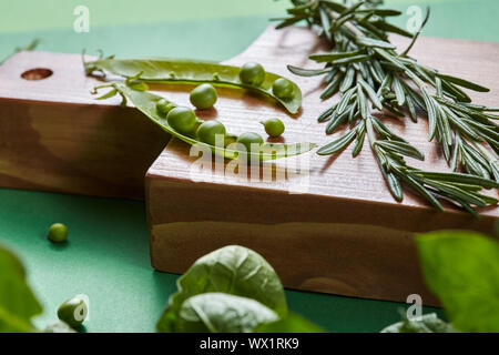 Grüne organische sauber Gemüse - Rosmarin, Hülsen, Erbsen, Bohnen, Spinat auf ein Holzbrett auf der Grünen. Stockfoto
