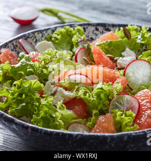 Frisch Ernährung Vegetarische Salat mit natürlichen organischen Gemüse, Zitrusfrüchte, in einer schwarzen Platte auf einem grauen Holz- Tabl Stockfoto