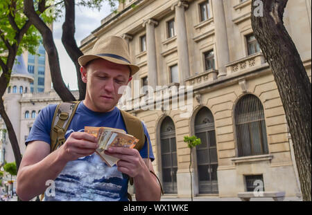 Junge männliche Touristen zählt Bargeld auf der Straße der Stadt Stockfoto