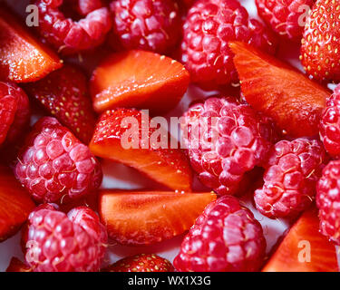 Nahaufnahme einer natürlichen organischen Hintergrund aus reifen Himbeeren und Erdbeeren Schnitte. Stockfoto