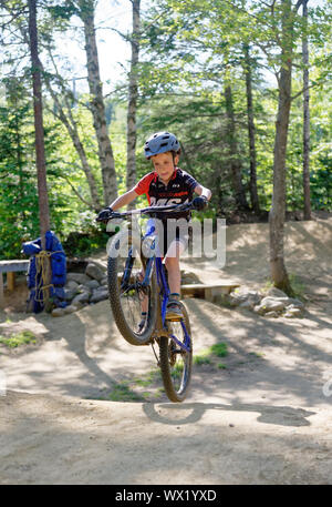 Ein sieben Jahre alter Junge knallen einem riesigen Wheelie auf seinem Mountainbike Stockfoto