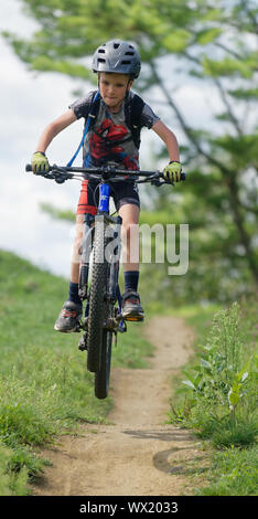 Ein sieben Jahre alter Junge Sprüngen auf seinem Mountainbike Stockfoto