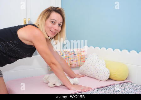 Junge Frau, die die kinder Bett Stockfoto