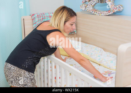 Junge Frau ihr Baby Kinderbett, Stockfoto