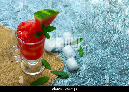 Erfrischende Wassermelonen Smoothie in ein Glas und ein Blatt Minze auf schwarzem Hintergrund. Kopieren Sie Platz. Stockfoto