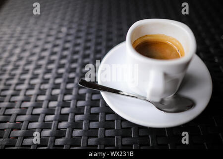 Details mit einem weißen Keramik Tasse Kaffee und eine Edelstahl Löffel auf eine Tabelle in einem Coffee Shop Stockfoto