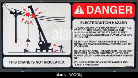 Ein Warnschild an einem Ausleger Kran, die zeigen, dass der Kran nicht von electroc Schock von Oberleitungen isoliert Stockfoto