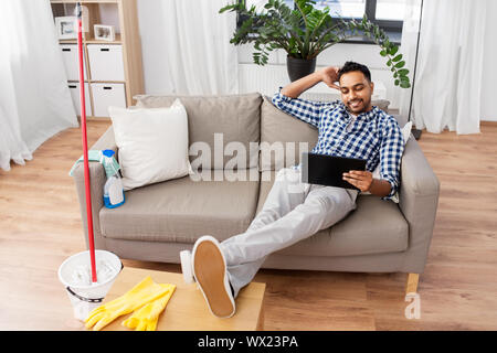 Mann mit Tablet Computer nach Hause Reinigung Stockfoto