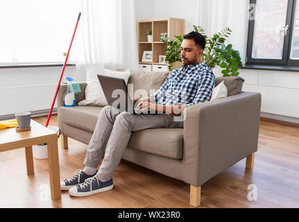 Mann mit Laptop nach Hause Reinigung Stockfoto