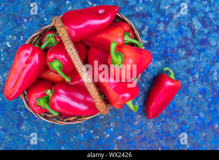 Rot (süß) Paprika in einem Weidenkorb auf blauem Hintergrund. Kopieren Sie Raum, Ansicht von oben. Stockfoto