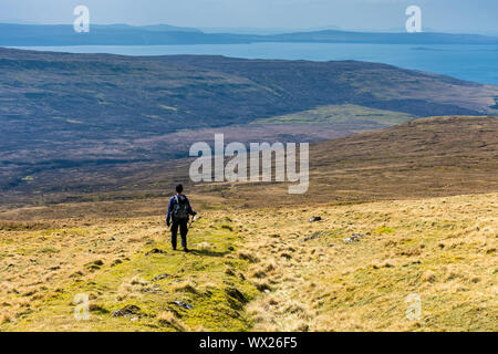 Ein Wanderer auf dem Rasen Deich, die aus dem bealach ein 'Mhòramhain auf der Trotternish Ridge in Glen Uig, Isle of Skye, Schottland, Großbritannien führt Stockfoto