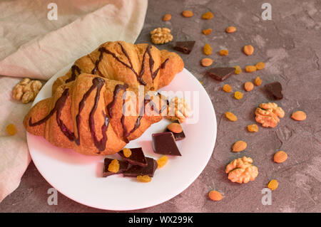 Zwei Schokolade croissant Rosinen und Nüssen auf grauem Hintergrund. Frühstück Konzept. Stockfoto