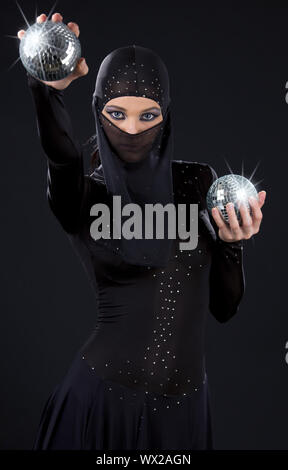 Partei-Tänzerin in Ninja-Kleid mit Disco-Kugeln Stockfoto
