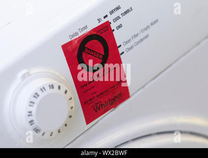 Rote Warnschild klemmt auf der Vorderseite eines weißen Knallerkauf Whirlpool Wäschetrockner Stockfoto